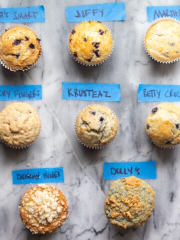 Eight blueberry muffins labeled by brands.