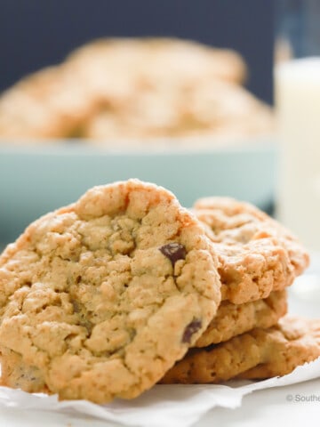 Stack of oatmeal chocolate chip cookies with a glass of milk.